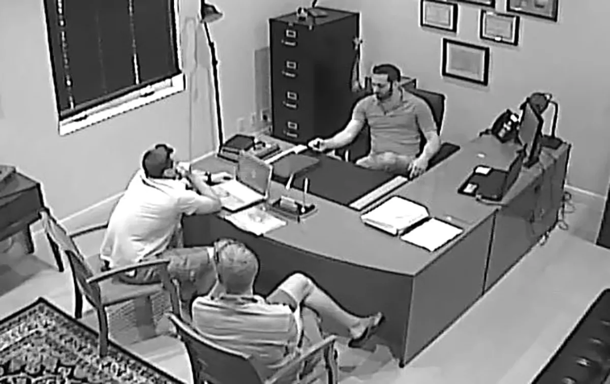 Surveillance-camera still: Guy Gentile seated across from two FBI agents inside his Bahamas brokerage office